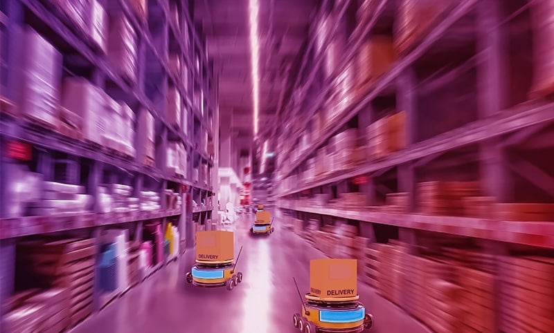 A hand in the foreground holding a smart phone with a smart monitoring app displaying. Industrial motors are in the background.